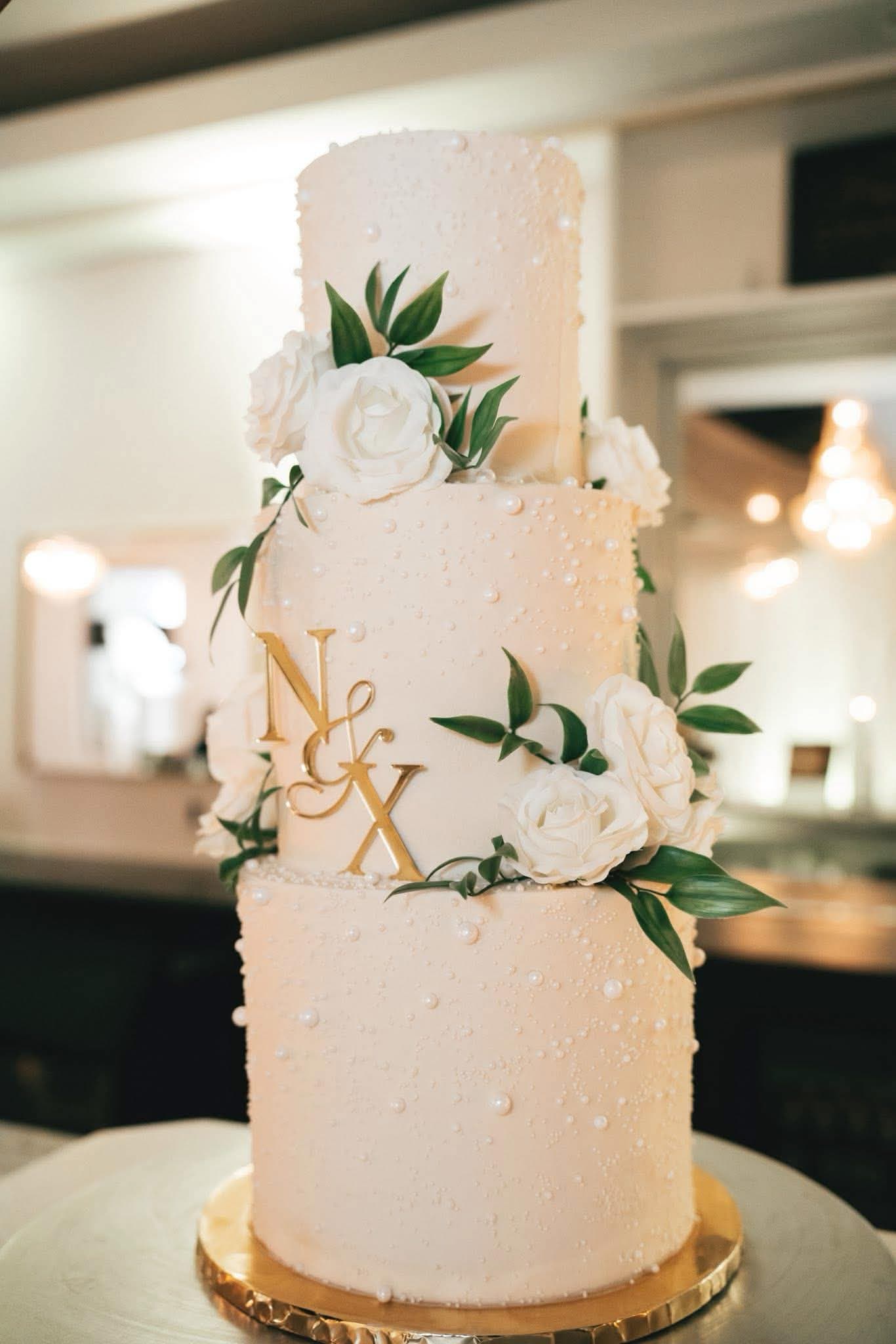 A white wedding cake with floral details on a dessert table.